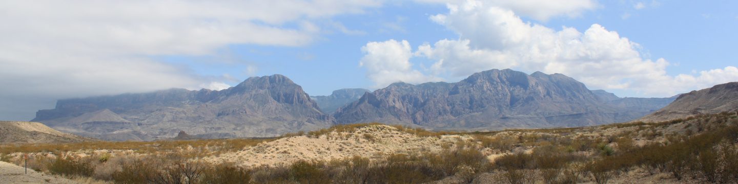 The Chisos Mountains rising above desert scrub under a partly cloudy sky
